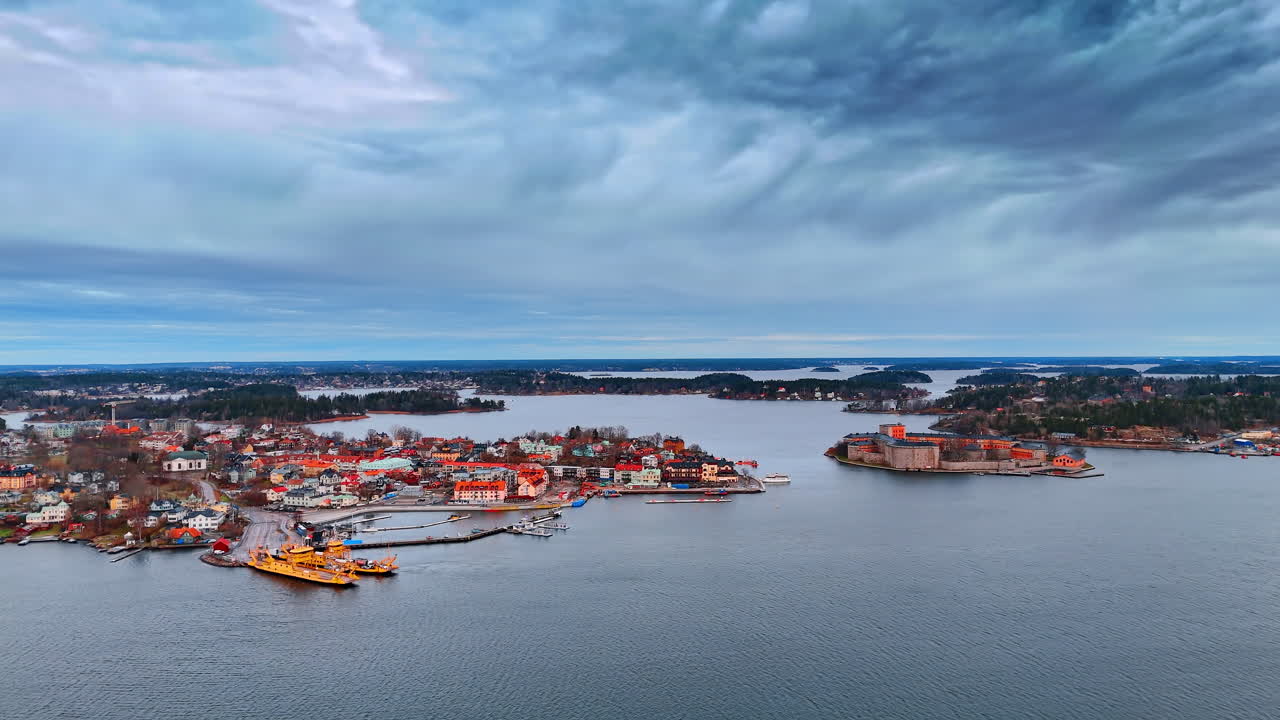 Aerial view of Vaxholm fortress and town with yellow ferry. Bird's eye view of a coastal town with historic stone fortress and ferry boat in the Stockholm archipelago