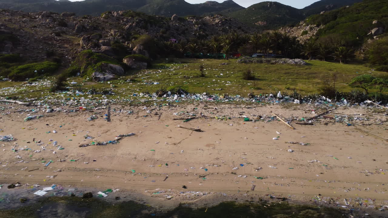 transporte aéreo de basura, desechos y suciedad en una playa de arena en vietnam durante la luz del sol - contaminación ambiental de la tierra en asia - hermoso paisaje montañoso en el fondo