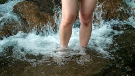 woman using her legs to soak in a natural waterfall