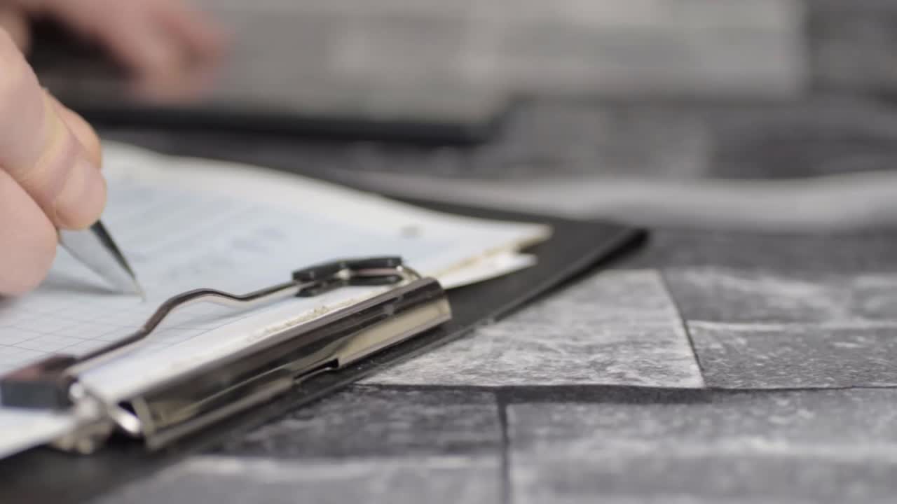Hand writing on graph paper on clipboard close up panning shot