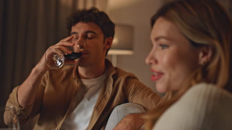 Relaxed spouses drinking wine relaxing together at cozy home evening close up.