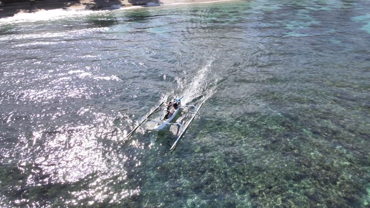 Aerial View of Traditional Outrigger Boat Moving Across Clear Tropical Water