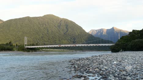 time lapse of colourful sunset over mountains around long, old steel bridge