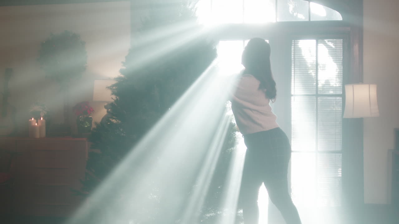 Woman moving a Christmas tree in a brightly lit room