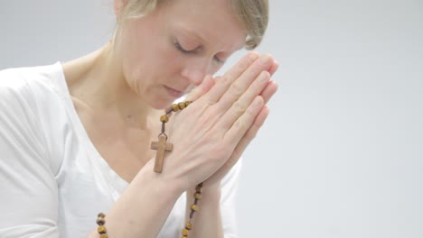 woman praying and holding cross in her hands on white background stock video