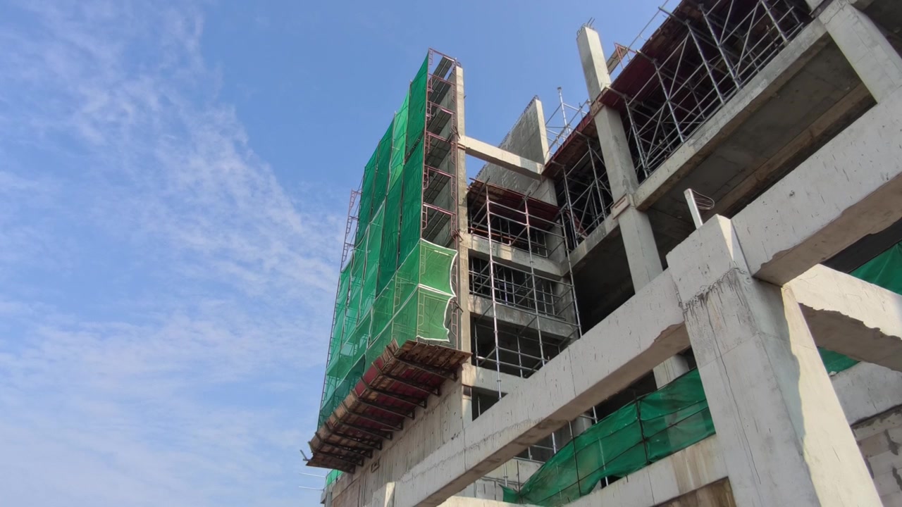 Una plataforma de trabajo en voladizo sostenida por soportes de andamio en un edificio. Contiene andamios adicionales utilizados para la construcción de muros exteriores.