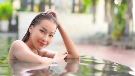 Joven-Mujer-Asiática-Seductora-Con-El-Pelo-Mojado-Posando-Para-Una-Cámara-En-La-Piscina