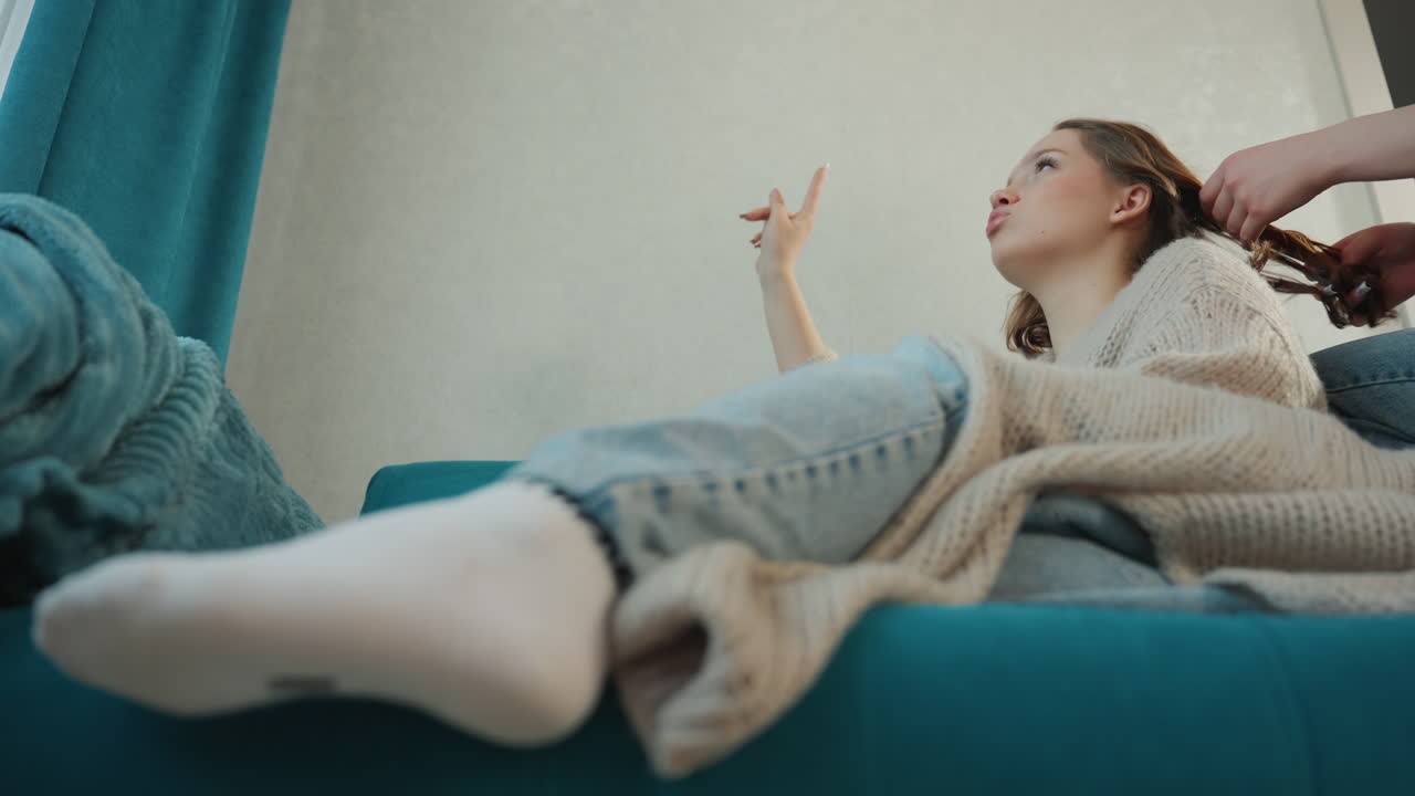 Relaxed Playful Scene, Teen Relaxing With Friends At Home, Teen Girl Having Fun With Friend During Relaxing Evening, Youthful Friends Sharing Laughter While Doing Hair At Cozy Home Gathering