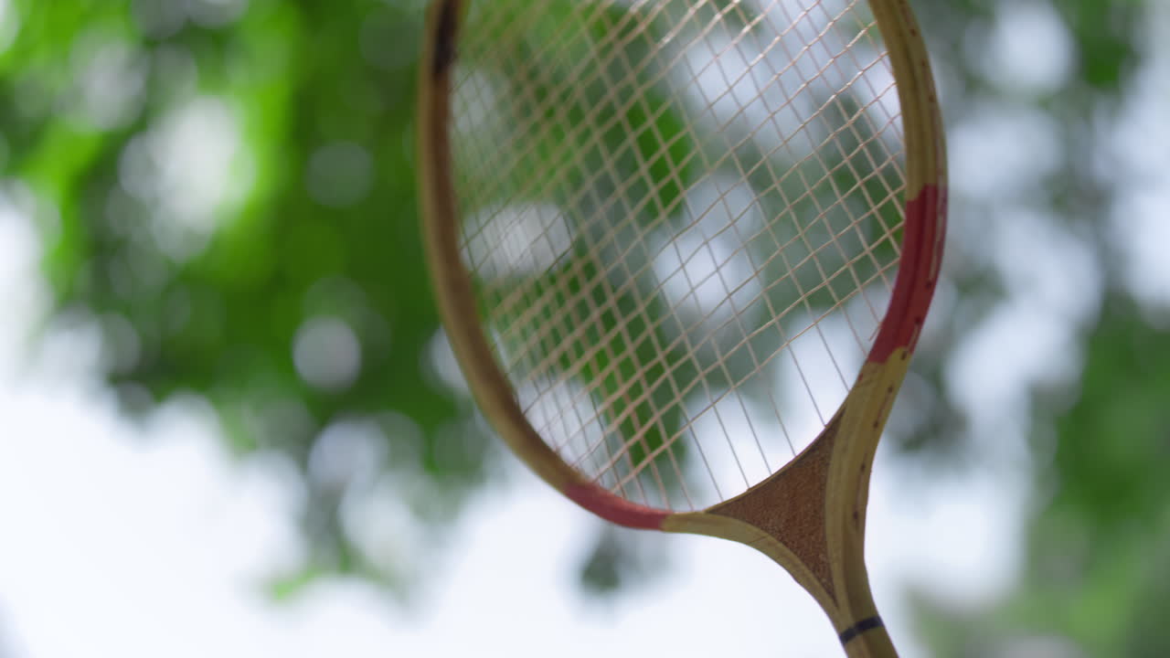 공원에서 여름날 배드민턴 라켓을 만지는 클로즈업 손. 활동적인 취미.
