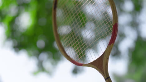mano de primer plano tocando la raqueta de bádminton en un día de verano en el parque. pasatiempo activo.