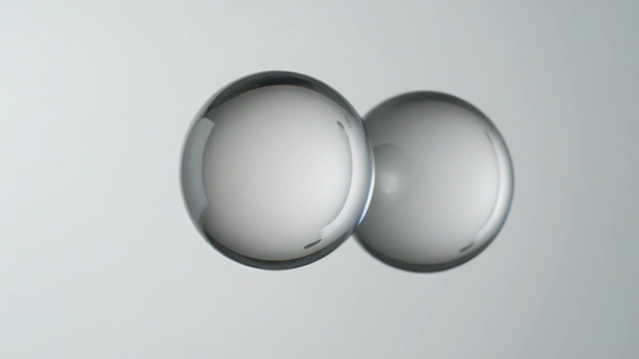 Shifting on playback, two glass spheres moving closer to camera and settling centered in studio