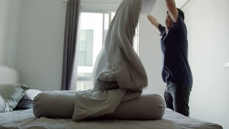 asian man at home making the bed - spreading a large and warm comforter over the bed and body pillow - slow motion