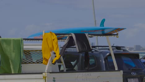 person preparing surfboard on vehicle at beach