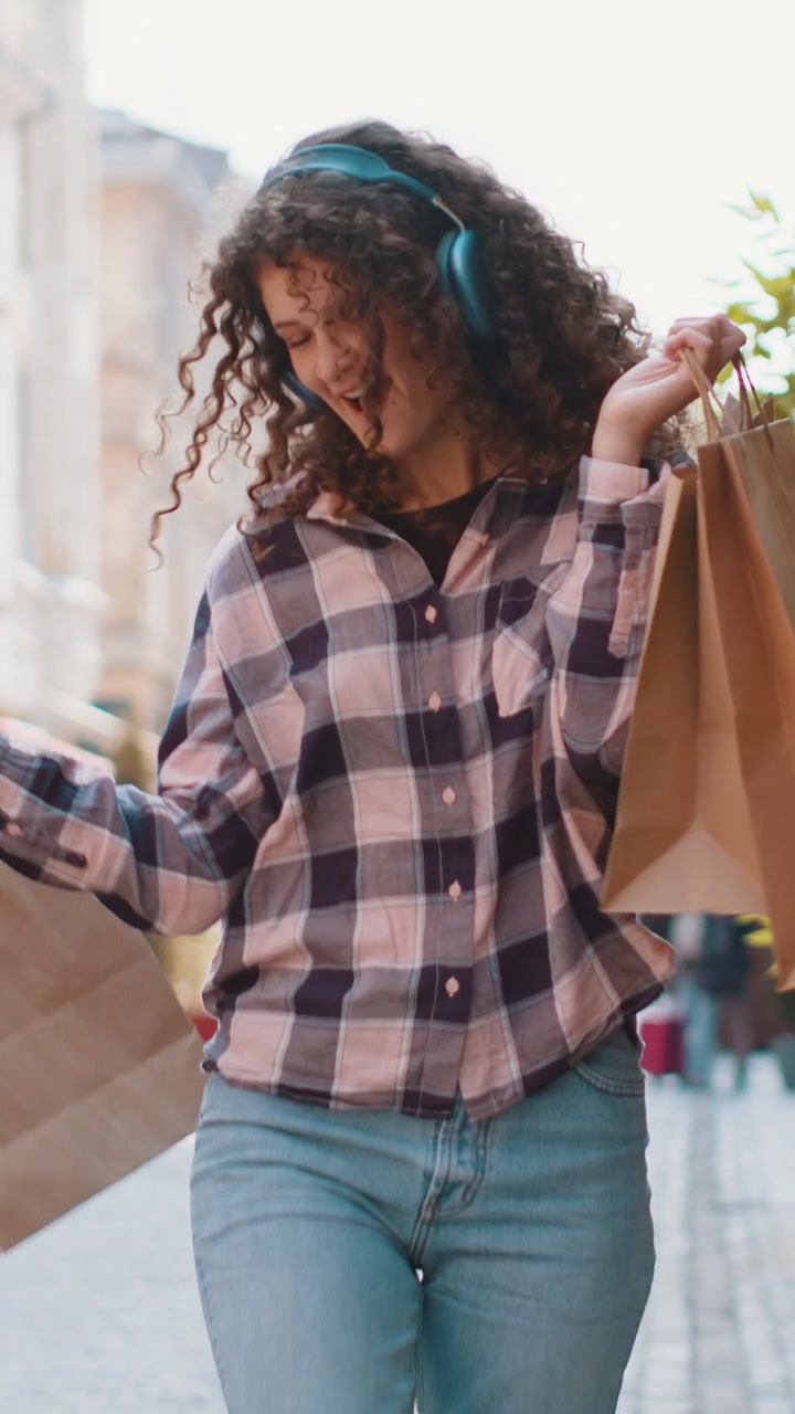 Giovane donna felice, maniaca dello shopping, consumatrice, dopo aver fatto acquisti durante i saldi, cammina per le vie della città con le borse piene