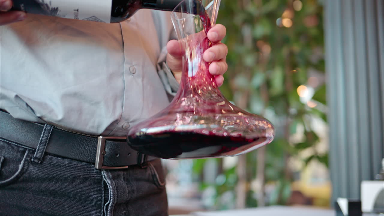 Red wine being poured in a wine decanter at a restaurant table