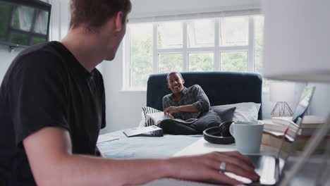 two male college students in shared house bedroom studying together