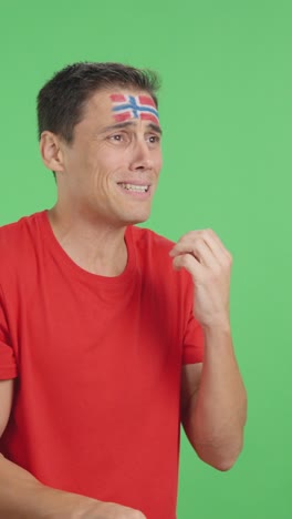 nervous man cheering for norway during a match looking away