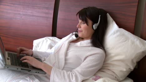 smiling woman using a laptop with headset on