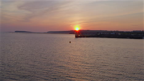 aerial low approach to blackrock diving board salthill promenade galway ireland, surrounded by calm atlantic waters as the sun sets on the horizon
