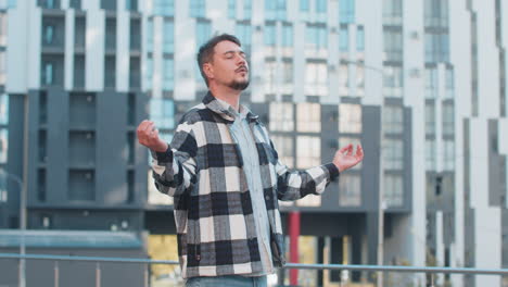 mature man tourist with arms outstretched meditating with closed eyes standing on downtown street