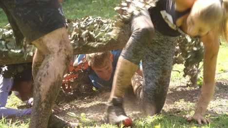 competitors help each other through net on an assault course