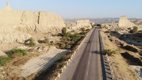 aerial view over along empty highway road through hingol national park in balochistan desert landscape with motorbike going past