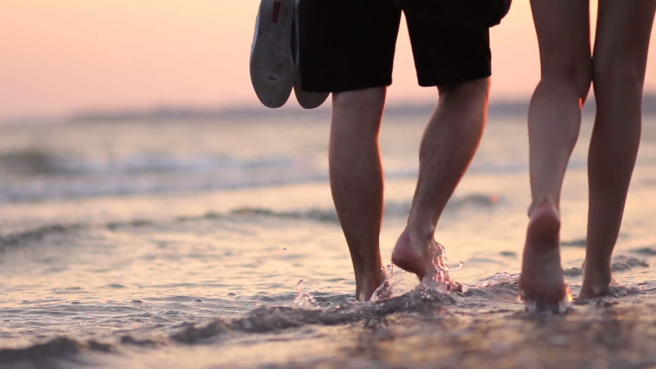 Vacations On The Idyllic Beach. Legs of the young man and woman during amazing sunset