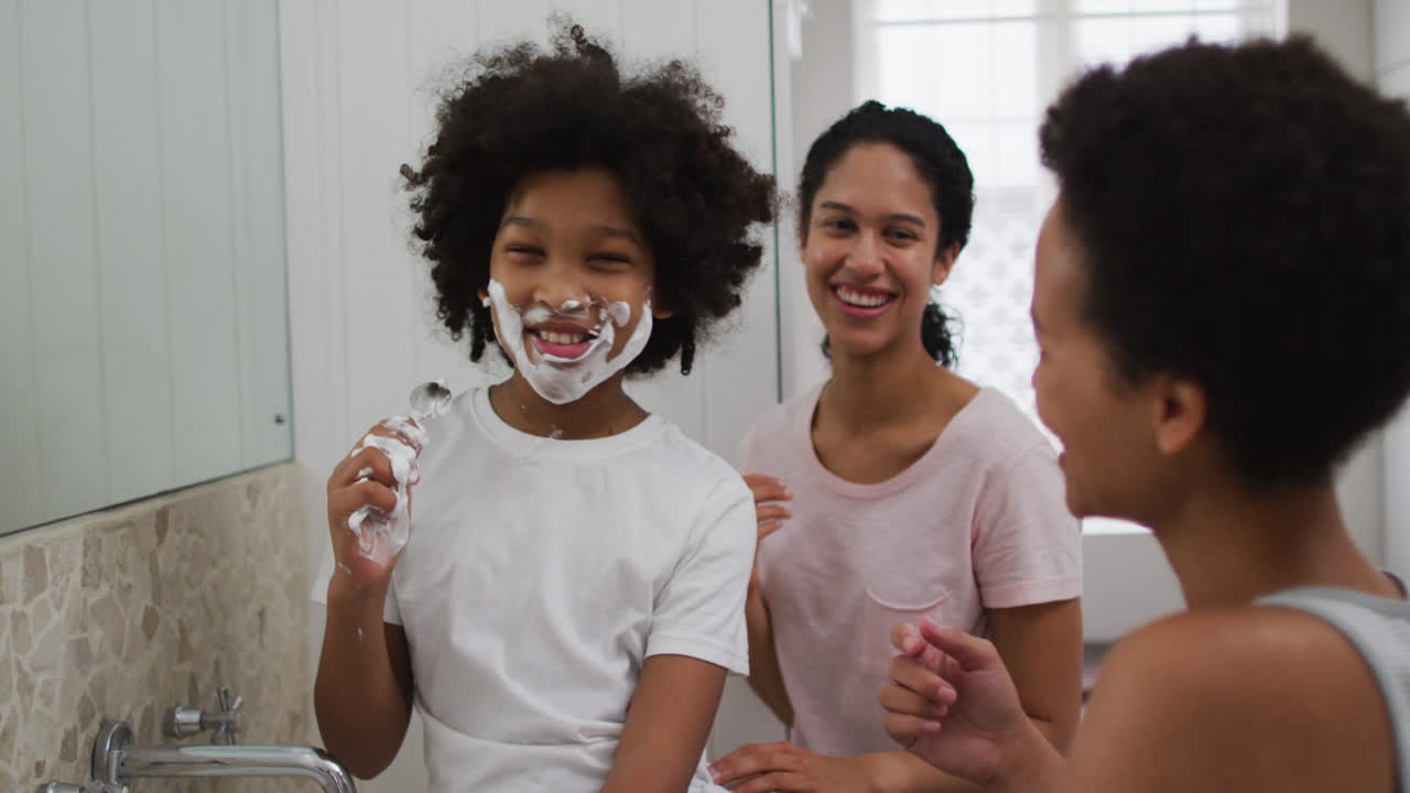 Mixed race mother and daughter having fun in bathroom