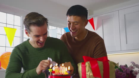pareja de hombres del mismo sexo celebrando su 30 cumpleaños en casa con el hombre recibiendo un regalo de su pareja