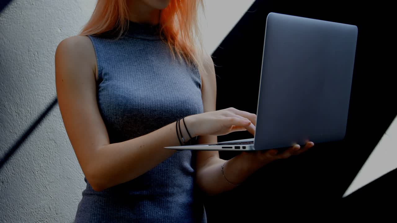 Woman holding laptop and typing, starting animated charts and globe over screen for tech analytics