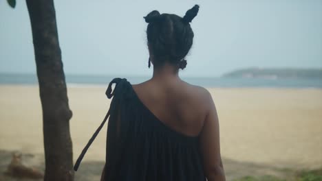 an indian adorned in a vibrant dress stands mesmerized, gazing at the vast ocean, its beauty and magnificence accentuated by the blurred background