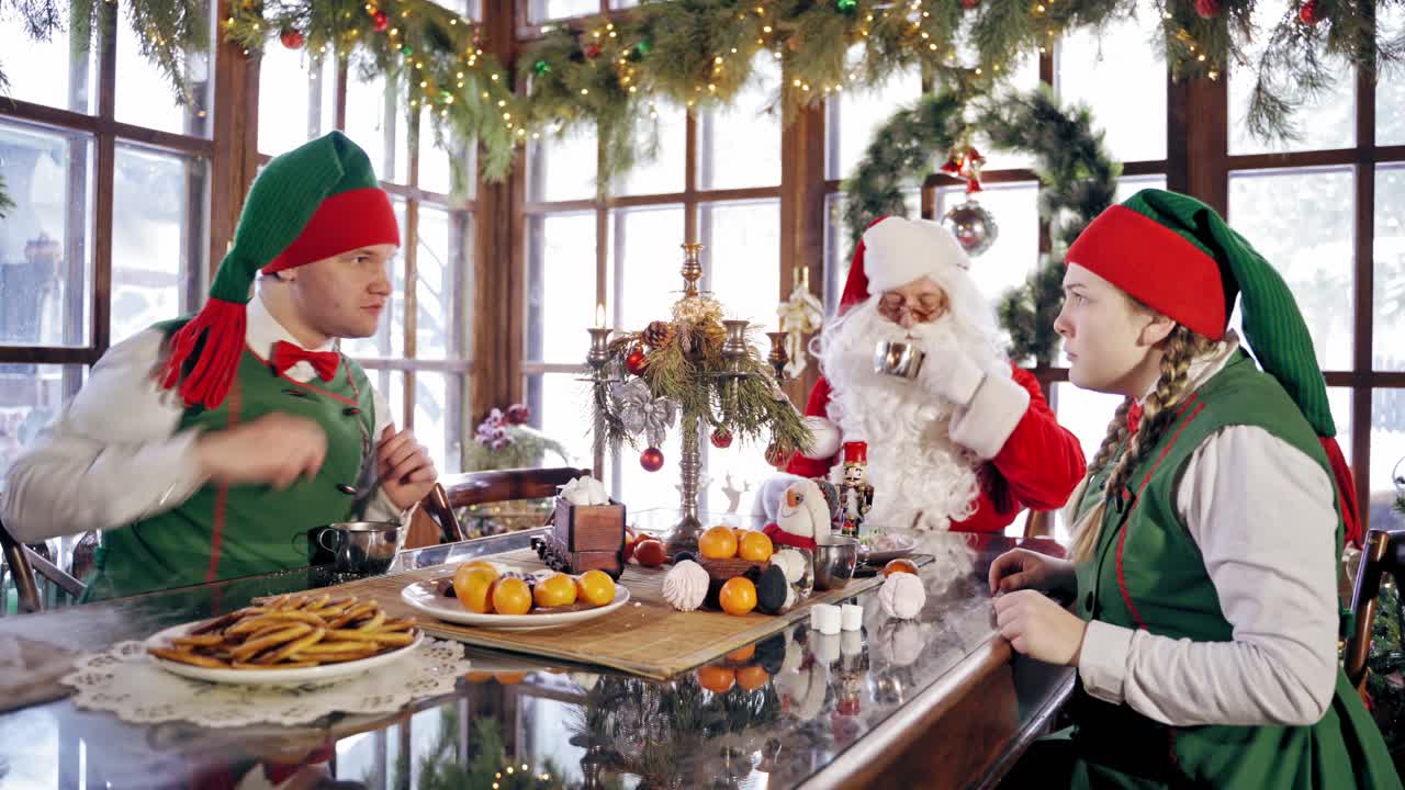 Santa Claus having dinner. Santa Claus with elves having dinner in decorated room