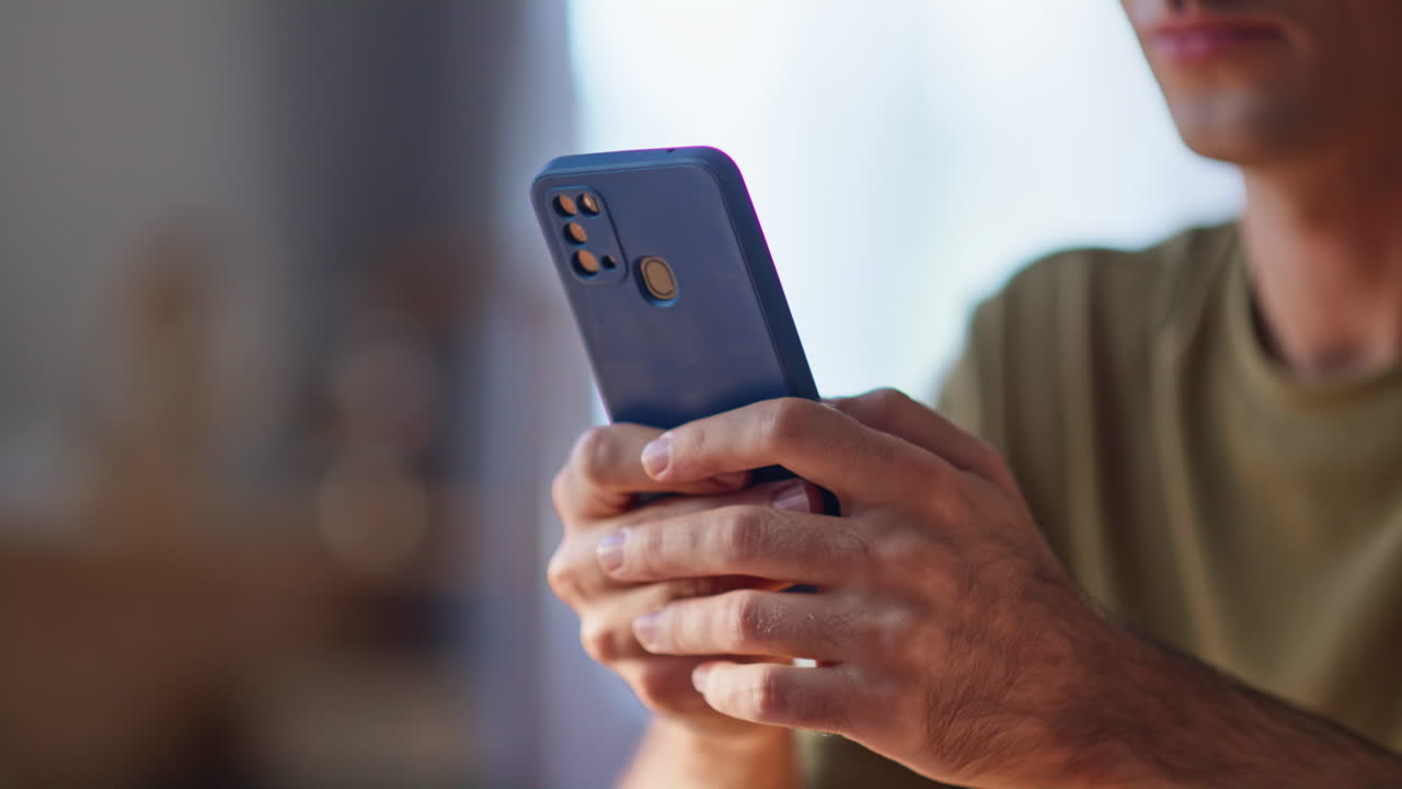 Closeup man hands texting cellphone in apartment. Businessman reading email