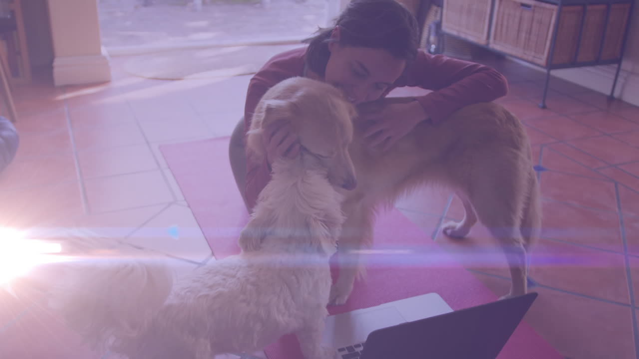 яркое пятно света против кавказской женщины, играющей со своими собаками дома