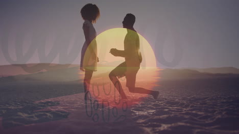 silhouetted couple walking on sandy beach with sunset in background