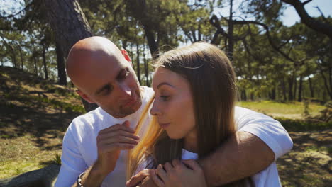 Beautiful-happy-young-couple-sitting-on-forest