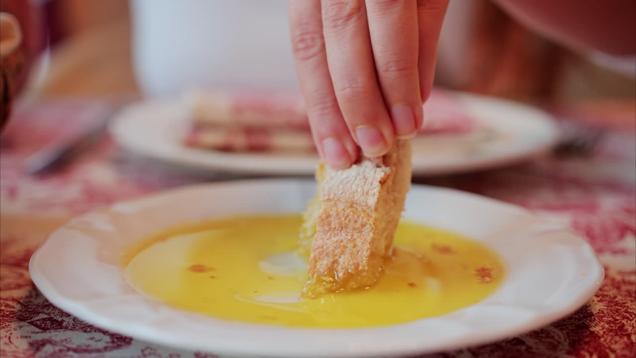 Close up of a woman dipping a piece of bread in an oil plate