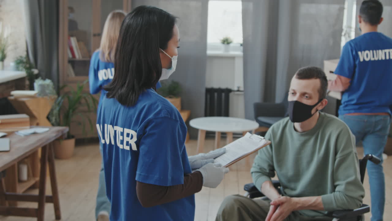 Team di volontari in magliette blu che aiuta un uomo con disabilità