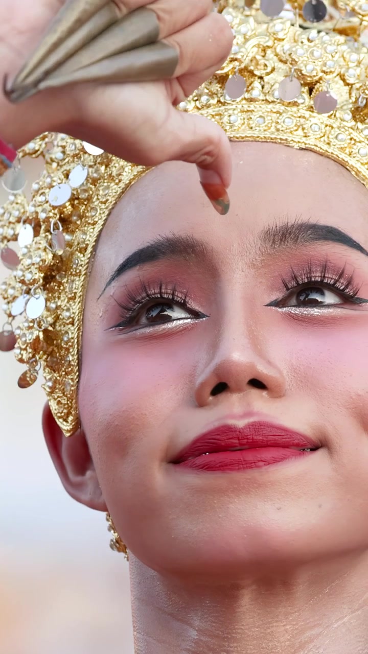 Close-up shot of a female dancer performing traditional Thai Khon in ornate golden costume.