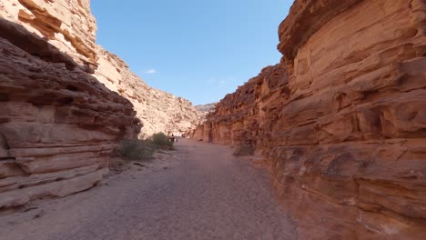 vista del cañón amurallado de arenisca sombreada en egipto con turistas en segundo plano