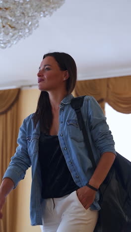 modern girl visiting historic building. young lady walks by the ball room where couple in old-fashioned clothes perform a dance. past meeting present. vertical video