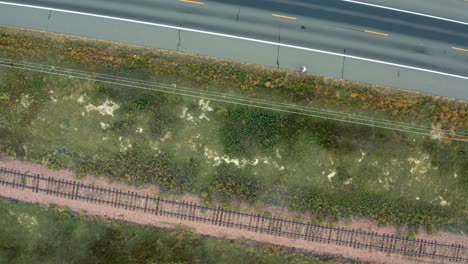 overhead of man walking on highway next to railroad tracks