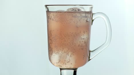 vaso elegante con fondo blanco y agua de rosas con gas y hielo.