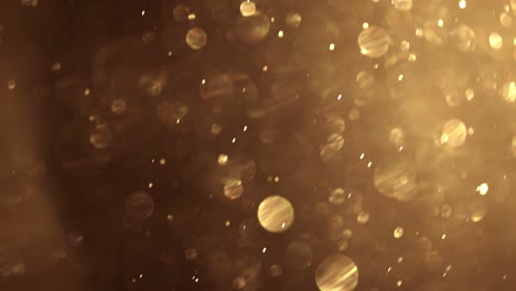 las partículas de polvo dorado vuelan en el aire. un fondo de bokeh dorado brillante y reluciente.