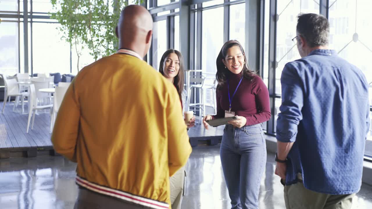 Wanita India menyerahkan papan klip dan berjabat tangan dengan rekan saat tim mendiskusikan keputusan di lounge.