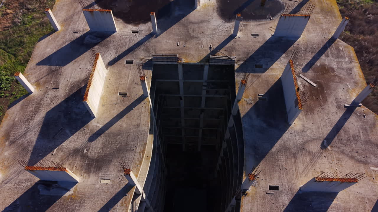 Aerial view of an abandoned construction site showing the concrete roof, pillars, and a large rectangular opening for stairs or elevator