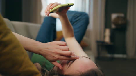 chica relajada acostada en el sofá viendo el teléfono inteligente en casa de cerca. dama escuchando música