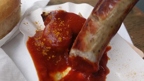 eating large currywurst sausage with hand