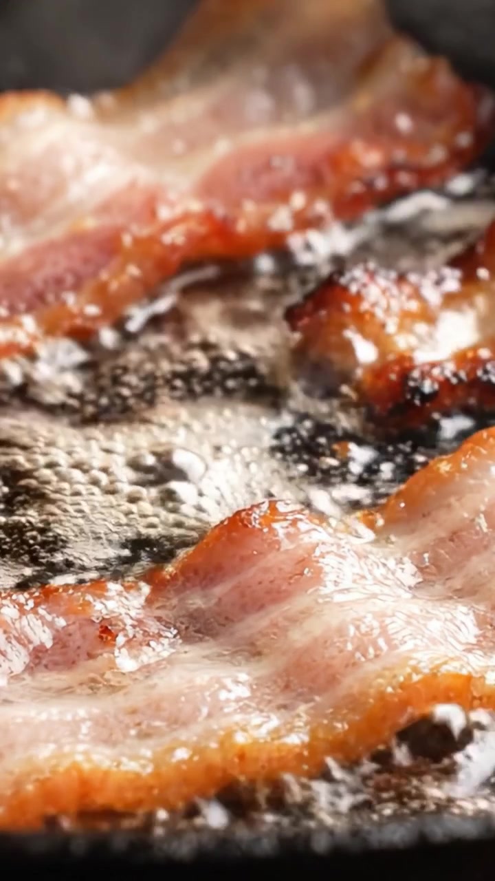 Sprødt bacon steger på en pande: Syngende strimler af velsmag, der forkæler med en salt aroma og mundvandsfremkaldende tekstur i en uimodståelig morgenmadsfornøjelse.