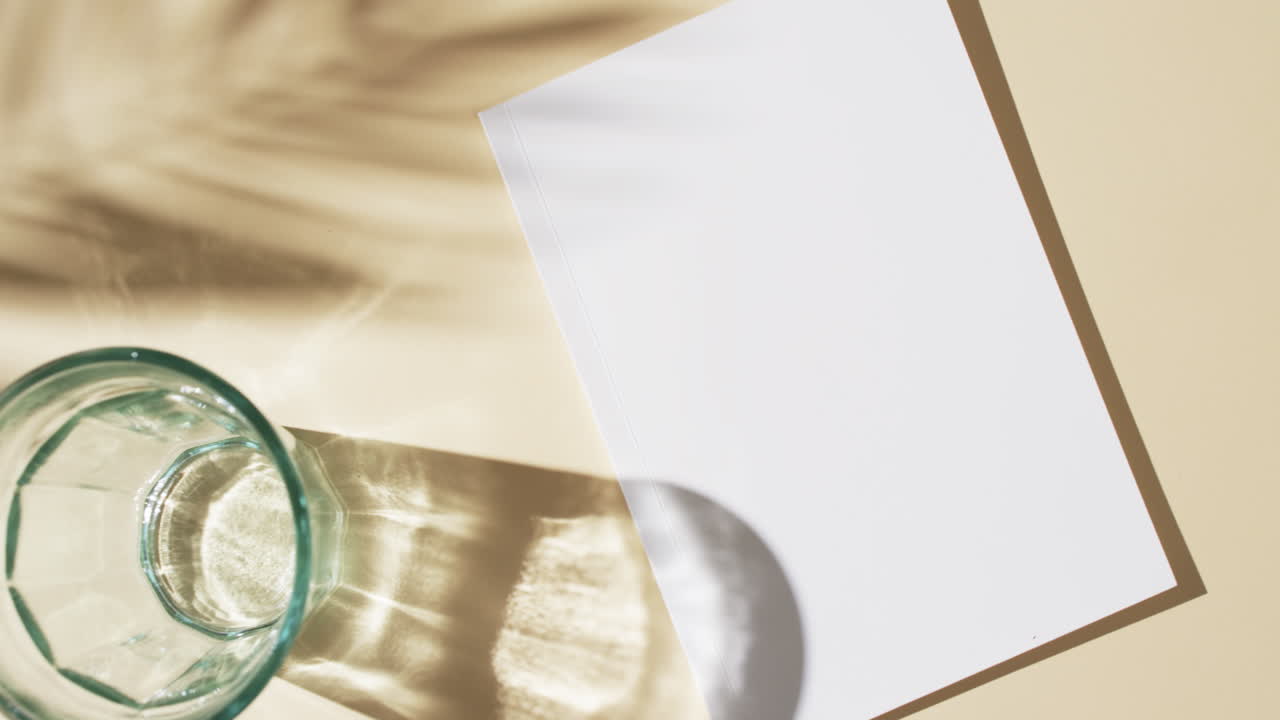 유리, 식물의 그림자, 빈  페이지와 노란색 배경의 복사 공간을 가진 책 위의 비디오